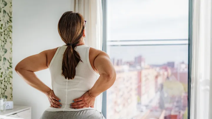 Woman sitting in bed with back pain