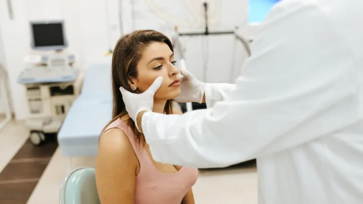 Doctor pressing on woman's sinuses