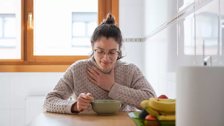 woman sitting at the kitchen table eating soup