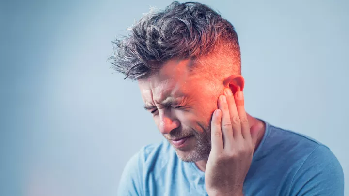 Man grabbing his ear in pain