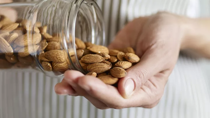 Close up of woman pouring almonds into her hand