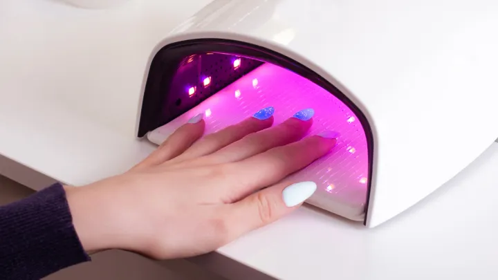 Woman's hand in UV nail dryer