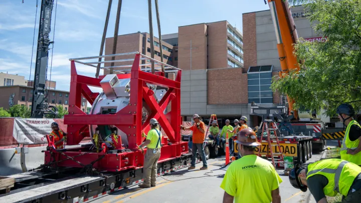 Proton therapy machine being lowered via crane.