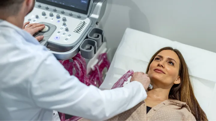 Doctor using ultrasound machine on woman's neck
