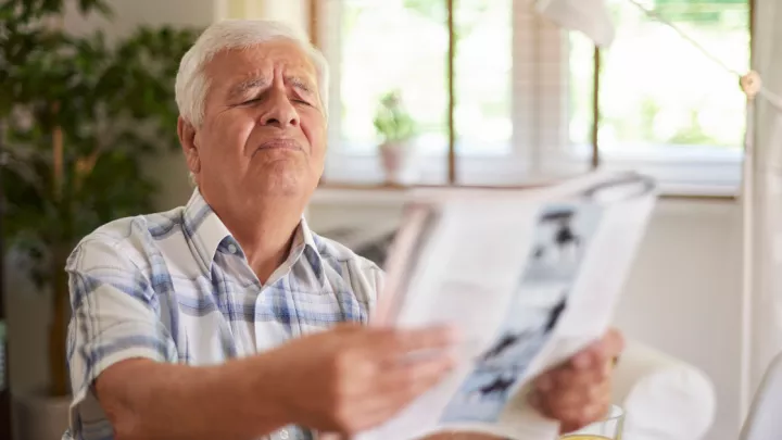 Older man squinting to read a magazine