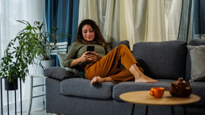 Barefoot woman lying on couch on her phone