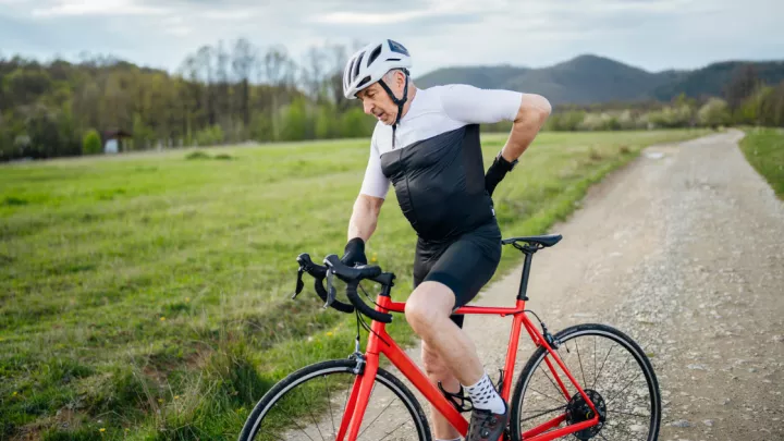 Older man on a bicycle with back pain