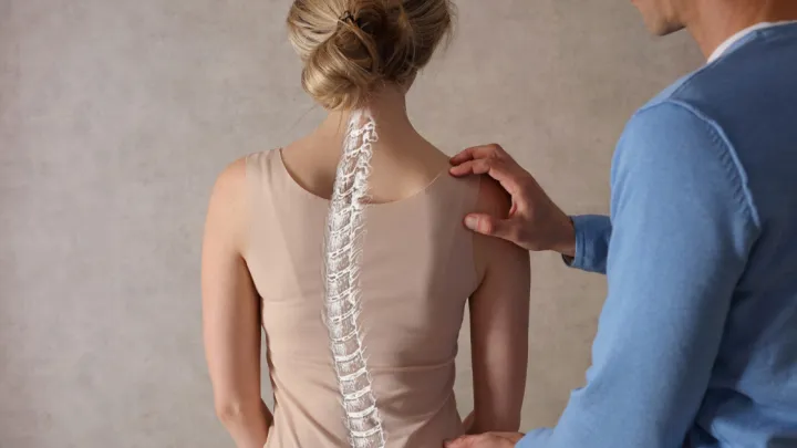 Provider examining woman's back with curved spine