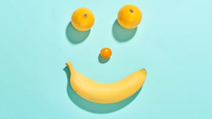 Smiley face made out of two oranges, a tomato and a banana