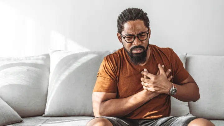 Man sitting on the couch holding his chest
