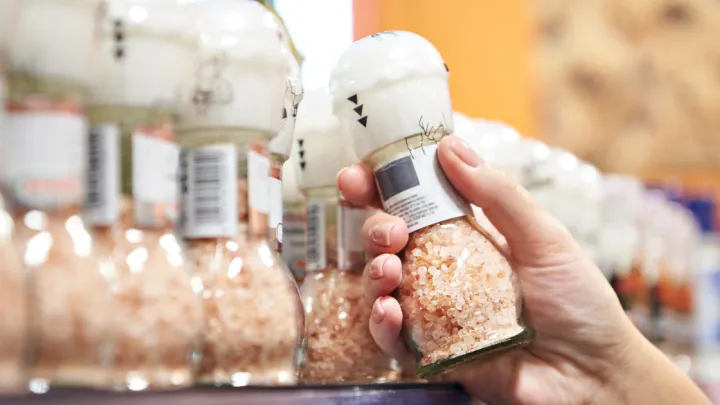 Woman grabbing Himalayan salt grinder off store shelf