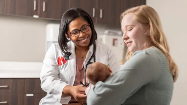 Woman holding baby talking to Nebraska Medicine doctor