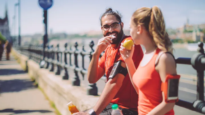 Man and woman sitting on bridge and eating