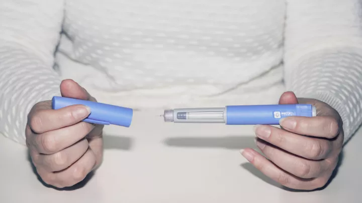 Close up of woman holding injection pen