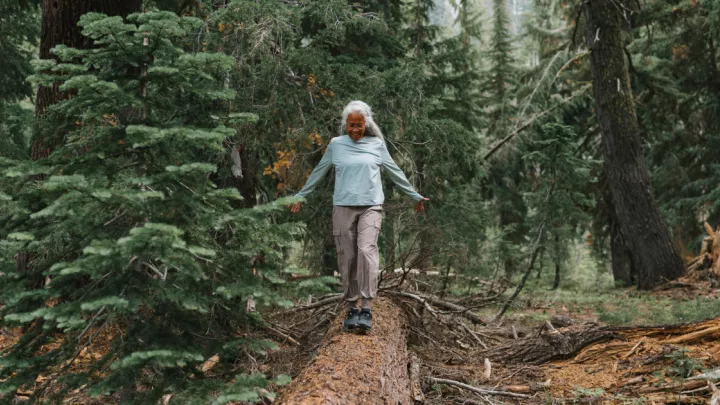 Older woman balancing on a fallen tree