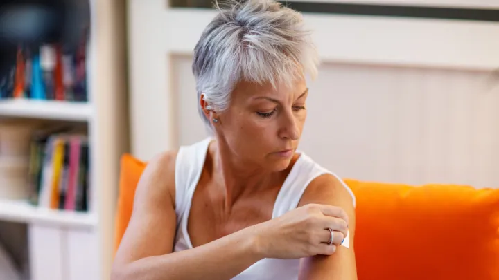 Woman putting patch on her arm