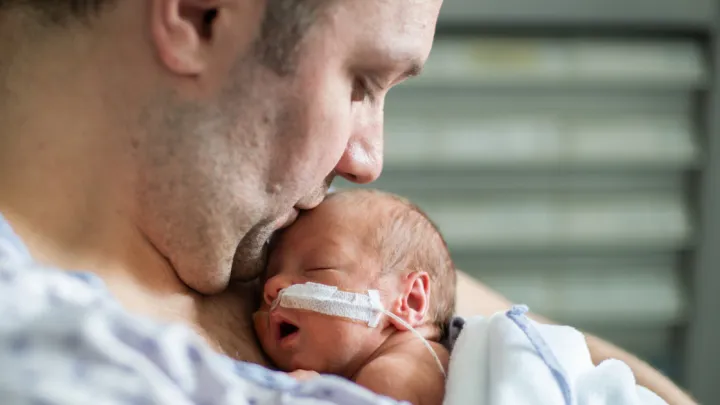 Dad holding infant in NICU