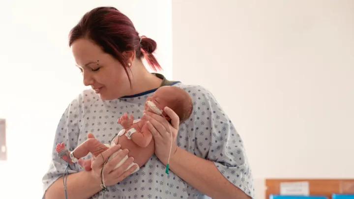 Woman holding her infant in the NICU