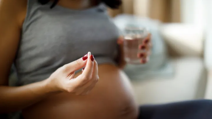 Pregnant woman holding pill