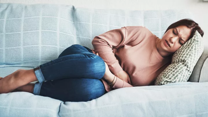 Woman lying on a couch with menstrual cramps.