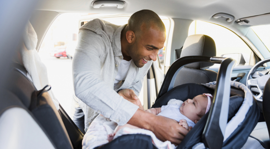 A parent tucking their child into a care seat.