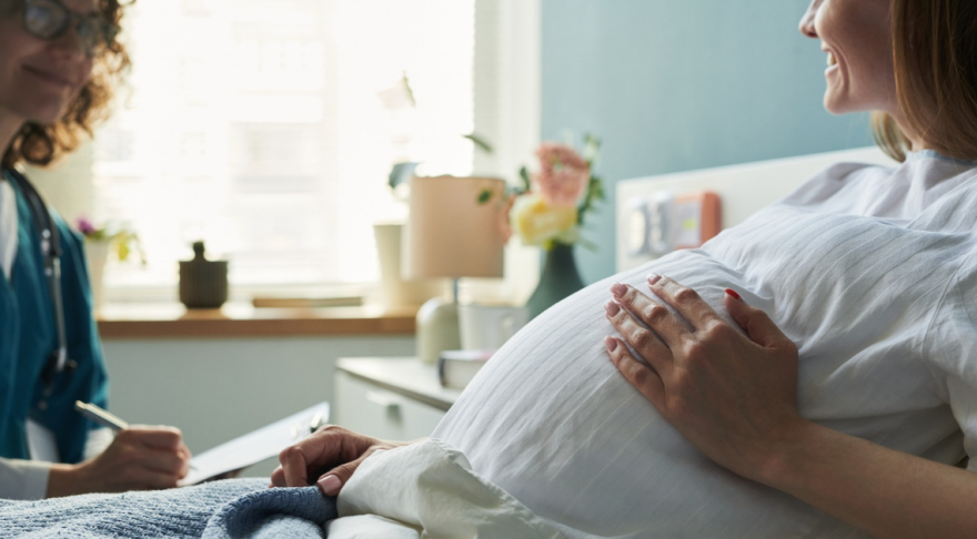 Pregnant woman in hospital bed talking to nurse