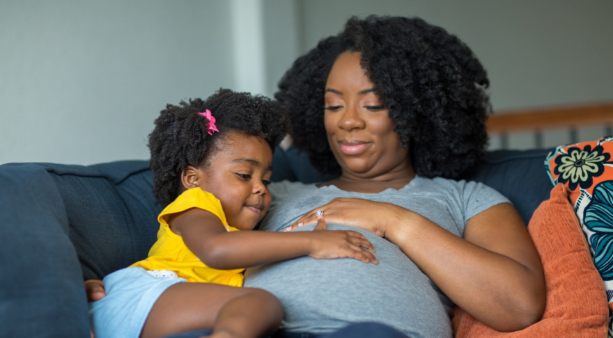 Pregnant woman sitting with young daughter